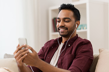 Image showing man in earphones listening to music on smartphone