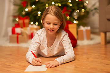 Image showing smiling girl writing christmas wish list at home