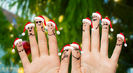 Image showing ten fingers in santa hats over christmas tree