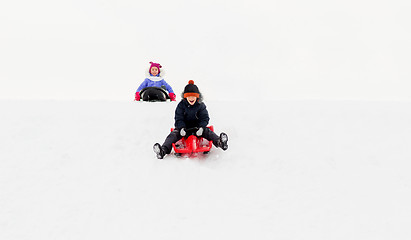 Image showing happy kids sliding on sleds down hill in winter