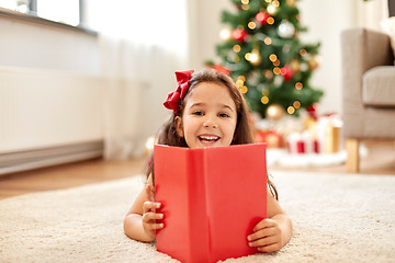 Image showing happy girl reading book at home on christmas