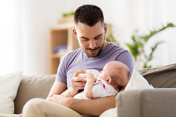 Image showing father feeding baby daughter from bottle at home