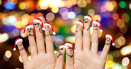 Image showing close up of ten fingers in santa hats over lights