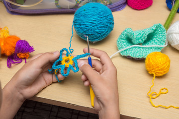 Image showing The girl knits a flower from thread, close-up