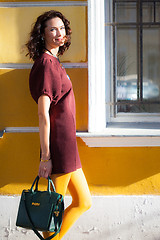 Image showing smiling european woman in a burgundy dress, mustard pantyhose an