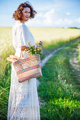 Image showing woman in white dress with basket with bread and milk walking alo