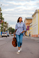 Image showing beautiful woman with a guitar walking down the street