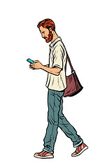 Image showing Bearded male pedestrian looks at a mobile phone