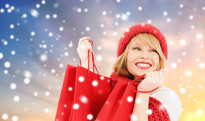 Image showing woman with red shopping bags over snow background