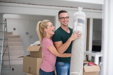 Image showing couple carrying a carpet moving in to new home