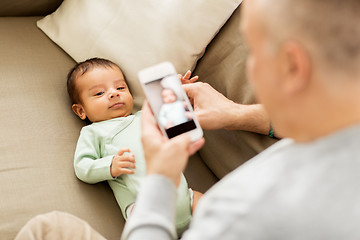 Image showing father photographing baby by smartphone