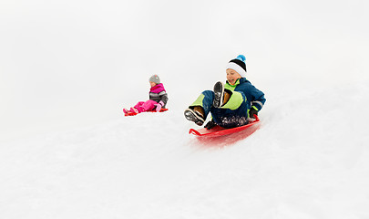 Image showing happy kids sliding on sleds down hill in winter