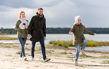 Image showing happy family walking along autumn beach