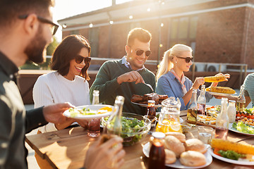 Image showing happy friends eating at barbecue party on rooftop