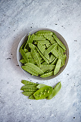 Image showing Fresh green peas in white ceramic bowl on gray stone background