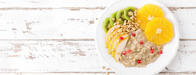 Image showing Sweet oatmeal porridge with pine nuts and fresh fruits - pear, o