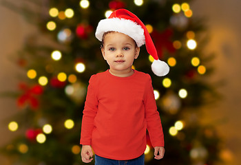 Image showing baby girl in santa hat over christmas tree lights