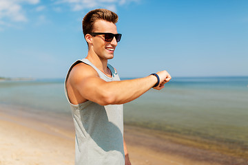 Image showing happy man with fitness tracker on summer beach