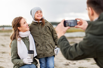 Image showing family photographing by smartphone on autumn beach