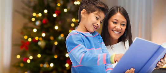 Image showing mother and daughter reading book on christmas