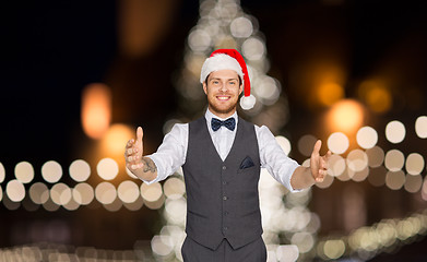 Image showing happy man in santa hat holding something imaginary