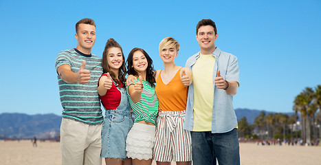 Image showing happy friends showing thumbs up over venice beach