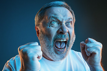 Image showing The senior emotional angry man screaming on blue studio background