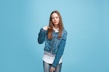 Image showing Beautiful female half-length portrait on blue studio backgroud. The young emotional teen girl