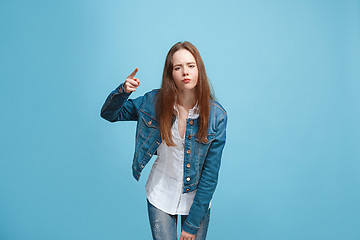 Image showing Beautiful female half-length portrait on blue studio backgroud. The young emotional teen girl