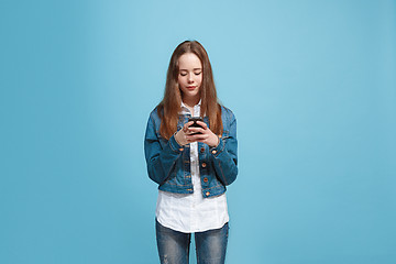 Image showing The happy teen girl standing and smiling against blue background.