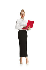 Image showing Full length portrait of a smiling female teacher holding a laptop isolated against white background