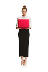 Image showing Full length portrait of a smiling female teacher holding a laptop isolated against white background