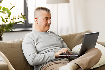 Image showing man with laptop computer sitting on sofa at home