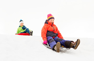 Image showing happy kids sliding on sleds down hill in winter