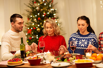 Image showing friends praying before christmas dinner at home 