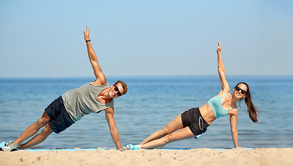 Image showing couple doing side plank exercise on summer beach