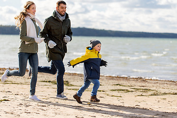 Image showing happy family running along autumn beach