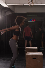 Image showing black female athlete is performing box jumps at gym