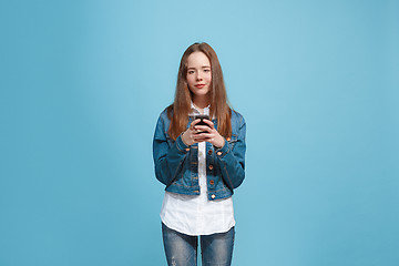 Image showing The happy teen girl standing and smiling against blue background.