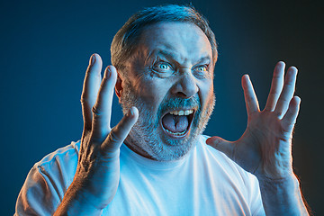 Image showing The senior emotional angry man screaming on blue studio background