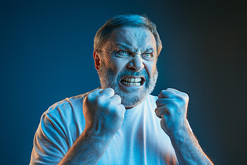 Image showing The senior emotional angry man screaming on blue studio background