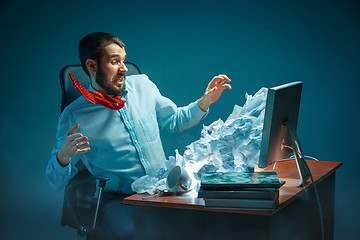 Image showing Young stressed handsome businessman working at desk in modern office shouting at laptop screen and being angry about spam