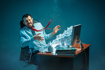 Image showing Young stressed handsome businessman working at desk in modern office shouting at laptop screen and being angry about spam