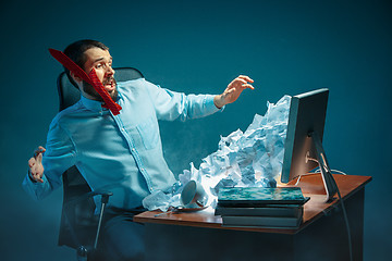 Image showing Young stressed handsome businessman working at desk in modern office shouting at laptop screen and being angry about spam