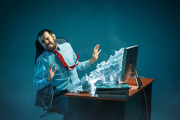 Image showing Young stressed handsome businessman working at desk in modern office shouting at laptop screen and being angry about spam