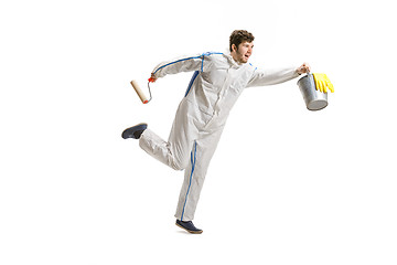 Image showing Young male decorator painting with a paint roller climbed a ladder isolated on white background.