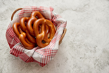 Image showing Basket with red and white checkered napkin filled with fresh brown pretzels