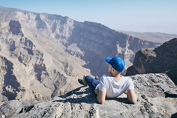 Image showing Tourist resting on the edge of cliff