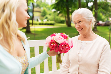 Image showing daughter giving flowers to senior mother at park