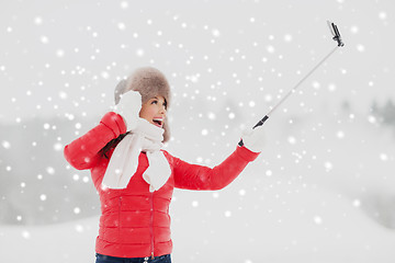 Image showing happy woman with selfie stick outdoors in winter